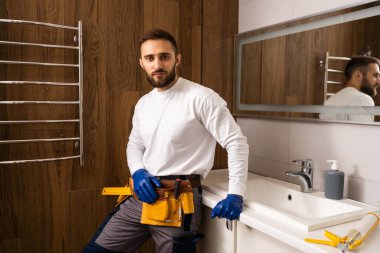 Profesyonel tesisatçı, üniformalı erkek işçi yeni daireye lavabo ve su borusu kuruyor..