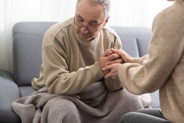 Genç fizyoterapistle rehabilitasyon işlemine katılan yaşlı bir erkek emeklinin başından vurulmuş. Yürüme engelli emekli bir adam profesyonel yardıma minnettar.