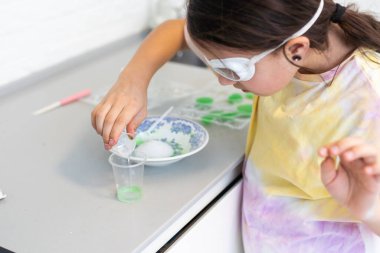 Çocuklar öğreniyor ve bilimsel deneyler yapıyorlar. Evde eğitim için bilim deneyi yapan küçük bir kız. Evdeki çocuklar için kolay ve eğlenceli bilimsel deneyler.