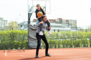 Baba ve kızı sokakta basketbol oynarken.