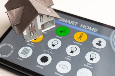 Küçük ev modeli ekran tabletinde ve ev elektronik cihazları ile kablosuz bağlantıda. Akıllı ev kontrollü ve Otomasyon sistemi teknolojisi