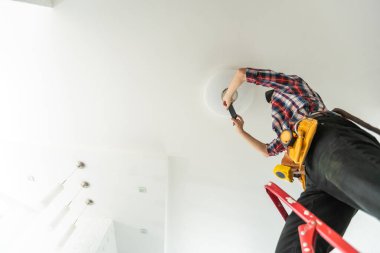 Elektrikçi tavan lambasına ampul takıyor. Yüksek kalite fotoğraf