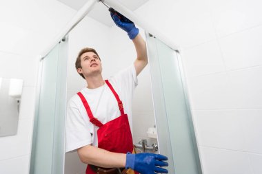 İşçiler duş kabininin cam kapağına silikon conta takıyorlar.