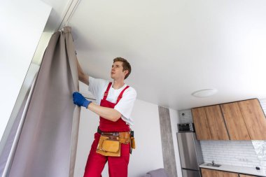 İşçi duvara pencere perdesi çubuğu yerleştiriyor.