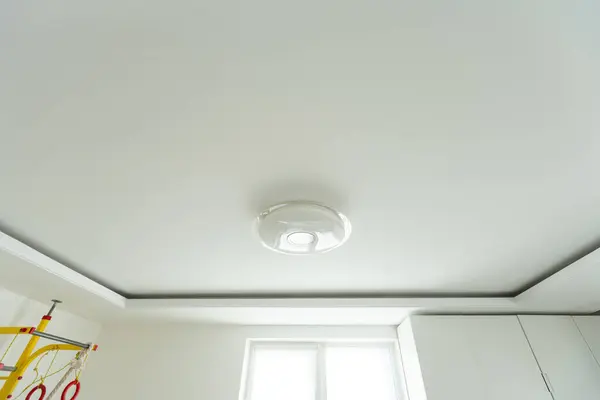 Round, minimalist, simple lamp on a white ceiling. A lamp that does not attract attention. High quality photo