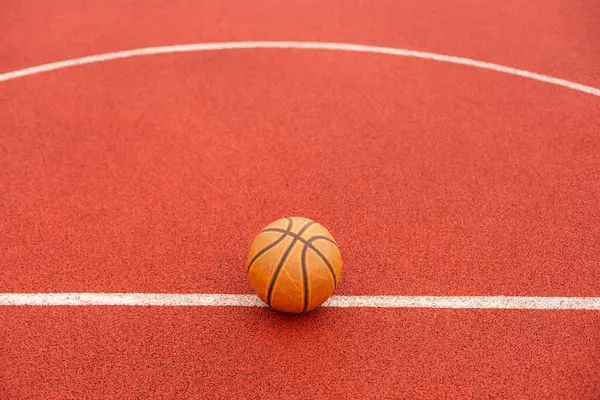 Basketbol topu yere düştü. Kırmızı sahada yakın çekim topu. Sokakta ya da kapalı sahada basketbol. İnsansız spor malzemeleri. Minimalizm. Şablon, spor geçmişi. Yüksek kalite fotoğraf