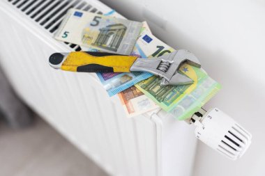 Dairedeki ısıtma bataryasının elle ısıtılması. Isıtma için para. Yüksek kalite fotoğraf