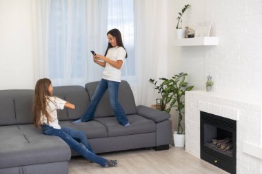 İki tatlı beyaz sarışın kız kardeş ellerinde cep telefonuyla gülüyorlar. Yüksek kalite fotoğraf