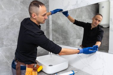 İşçi aynayı banyoya yerleştirir. Yüksek kalite fotoğraf