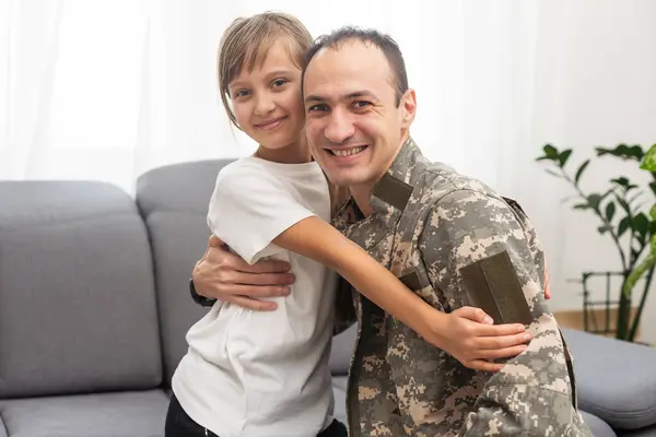 Little girl hugging her military father at home, closeup. High quality photo