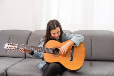 Güzel genç bir kız evde gitar çalar. Yüksek kalite fotoğraf