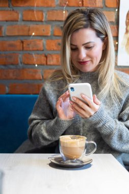 Şık takım elbiseli genç bir kadın dışarıda oturuyor ve akıllı telefon üzerinde çalışıyor. Yüksek kalite fotoğraf