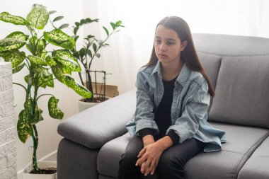 Arka plandaki kanepede oturan güzel genç kız. Uzayı kopyala ve taklit et. Yüksek kalite fotoğraf