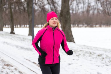 Açık hava spor egzersizleri, spor kıyafetleri fikirleri. Sıcak spor giysili bir kadın kış boyunca dışarıda koşuyor. Yüksek kalite fotoğraf