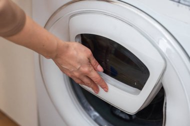 Kadın modern çamaşır makinesini kapalı mekanda açıyor, yakın plan. Yüksek kalite fotoğraf