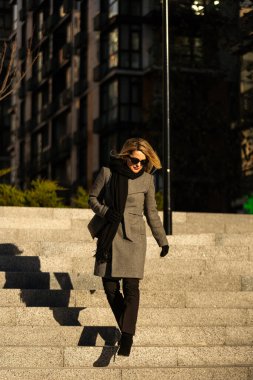 Paltolu kız güneşli bir günde şehirde dolaşır. Yüksek kalite fotoğraf