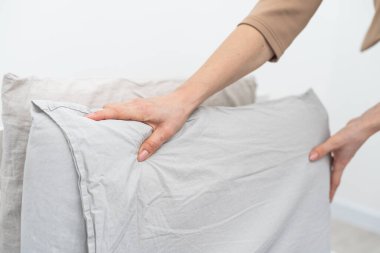 Kadın sabah yatağı toplarken yastığı ayarlıyor. Yüksek kalite fotoğraf