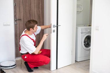 İç kapıların delinmesi ve kurulumu, zanaatkar kapı çerçevesinde el matkabı, kapı ve kurulum ile bir delik açar.