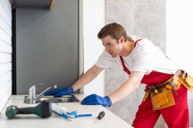 Tesisatçı mutfaktaki musluktan su akışını kontrol ediyor, yakın plan. Onarım servisi.