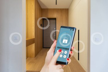 Akıllı ev, ev otomasyonu, uygulama simgeli aygıt. Kadın akıllı telefonunu akıllı güvenlik uygulaması ile evinin kapısını açmak için kullanıyor.