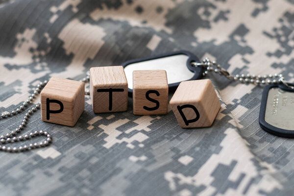 The letters PTSD on wooden blocks on a black background. Minimal concept post traumatic stress disorder. High quality photo