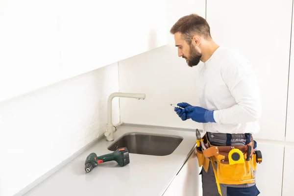 plumber installs kitchen faucet. refurbishment in the apartment