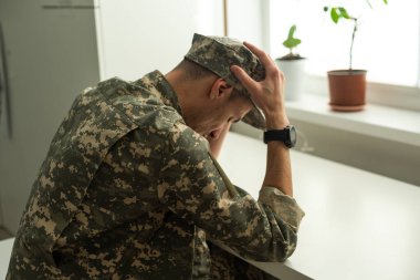 Boş bir odada oturan depresif üniformalı asker. Duvarda posterin için bir yer. Yüksek kalite fotoğraf