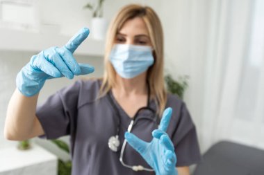 Yorgun kadın doktor. Koronavirüs. Koruyucu maskeli ve eldivenli genç bayan doktor parmak gösteriyor.