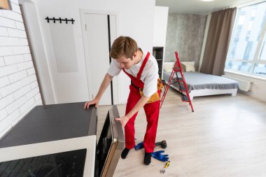 Ev aletlerinin bakım hizmetini kabul et. İşçi bulaşık makinesindeki filtreyi temizler. Erkek tamirci besin kalıntısı filtrelerini kontrol ediyor.