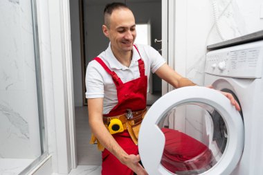 İç kısımda profesyonel bir tamirci çamaşır makinesini tamir ediyor. Yüksek kalite fotoğraf