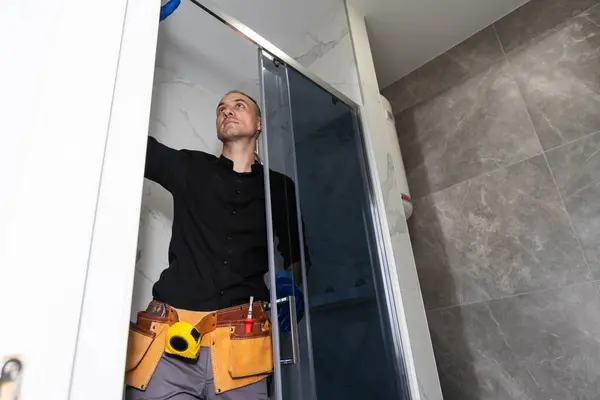 Professional handyman working in shower booth indoors. High quality photo