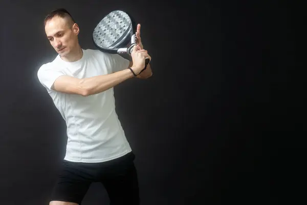 Man ready for paddle tennis serve in studio shot. High quality photo
