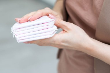 Genç, yetişkin bir kadın arka planda hijyenik havlu paketleri tutuyor. Pastel renk. - Yakın çekim. Mesaj için boş bir yer. Yüksek kalite fotoğraf