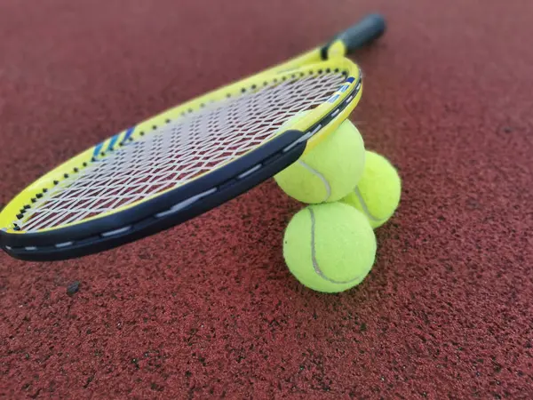Tennis. Tennis ball and racket on a red background of tennis court with copy space. Sport and healthy lifestyle. The concept of outdoor game sports. . High quality photo