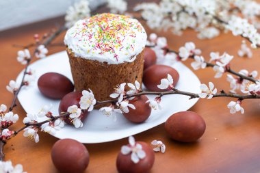 Paskalya pastası, boyanmış yumurta ve çiçek açan dal, ahşap masada bahar kompozisyonu..