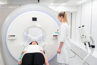 Modern hastane laboratuvarında bir hastaya tıbbi tomografi ya da MRI taraması yapın. Radyografi bölümünün içi. Beyaz odada teknolojik olarak gelişmiş ekipmanlar var. Manyetik rezonans tanılama makinesi.
