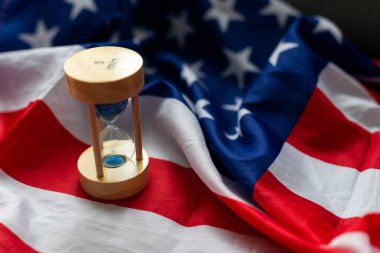 Hourglass and USA flag, soft focus, copy space. High quality photo clipart