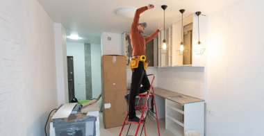 Elektrikçi tavan vantilatörünü içeride lambayla onarıyor. Metin için boşluk