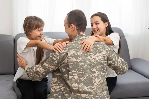 Little children hugging their military father at home. High quality photo