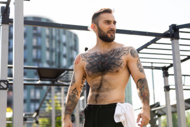 Genç adam parkta egzersiz makinesinin üzerinde antrenman yapıyor..