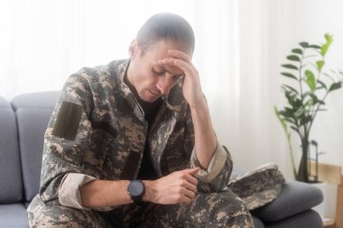 Gergin erkek asker depresyonda, evde tek başına oturuyor, travma sonrası stres bozukluğu konsepti. Yüksek kalite fotoğraf