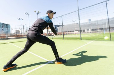 Ağ arkasında yeşil çim bir padel kortunda padel oynayan adam. Yüksek kalite fotoğraf