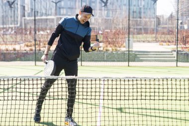 Ağ arkasında yeşil çim bir padel kortunda padel oynayan adam. Yüksek kalite fotoğraf