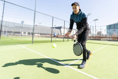 Ağ arkasında yeşil çim bir padel kortunda padel oynayan adam. Yüksek kalite fotoğraf