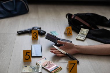 Kurbanın eli kanıt işaretleri ve apartman dairesinin zemininde bulunan eşyalarla çevrili. Olay yeri inceleme ve belgelendirme süreci. Yüksek kalite fotoğraf