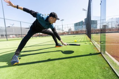Ağ arkasında yeşil çim bir padel kortunda padel oynayan adam. Yüksek kalite fotoğraf