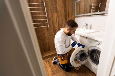 Professional plumber with plunger and instruments near sink