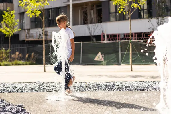 Sıcak bir yaz gününde şehir parkındaki çeşmede dans eden mutlu genç kız. Yüksek kalite fotoğraf
