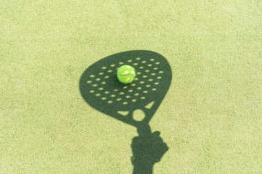 Yeşil çimlerin üzerinde sarı bir top olan padel raketinin gölgesi. Yüksek kalite fotoğraf