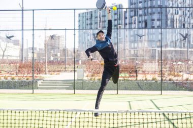 Ağ arkasında yeşil çim bir padel kortunda padel oynayan adam. Yüksek kalite fotoğraf